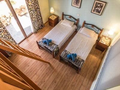 Bird's eye view of two twin beds in a hotel room with wooden floors.