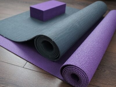 Photo of grey and purple exercise mats rolled up on floor.