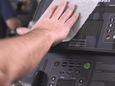 Photo of person's hand wiping gym equipment.