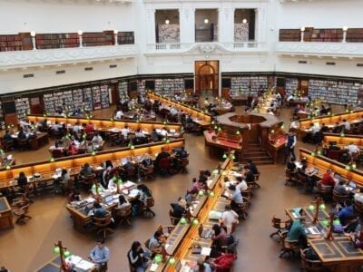 Photo of many people sitting at desks in a college library.