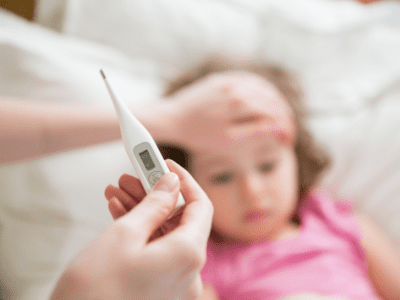 Photo of mother holding thermometer with hand on her daughter's forehead.