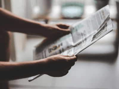 Close up photo of hands holding a newspaper.