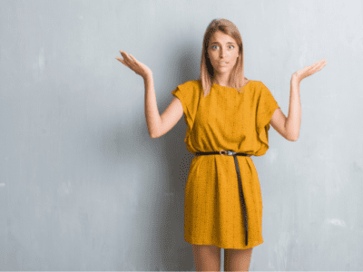 Photo of young woman in yellow dress shrugging.