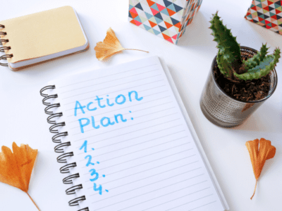 Photo of lined paper with "Action Plan" written on it, a pen, small cactus and dried ginkgo leaves.