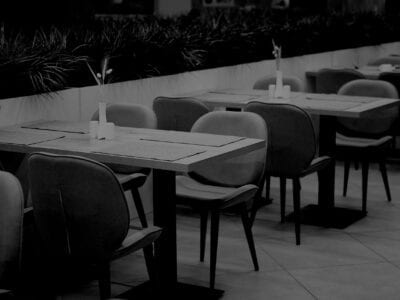 Black and white photo of tables and chairs in restaurant.